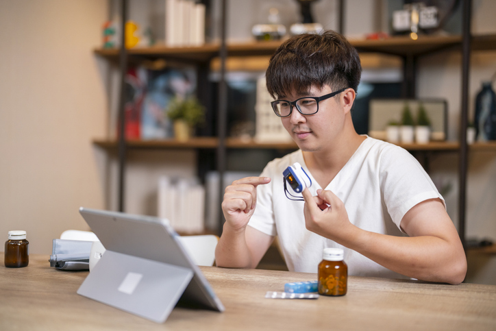 man in bed looking at screen of laptop and consulting with a doctor online at home, telehealth